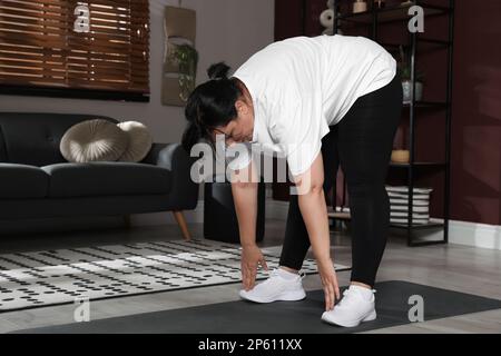 Übergewichtige, reife Frau, die zu Hause Sport macht Stockfoto