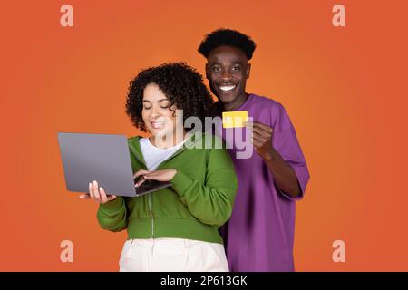 Glückliche Liebhaber gemischter Rennen, die online einkaufen, mit einem Laptop Stockfoto