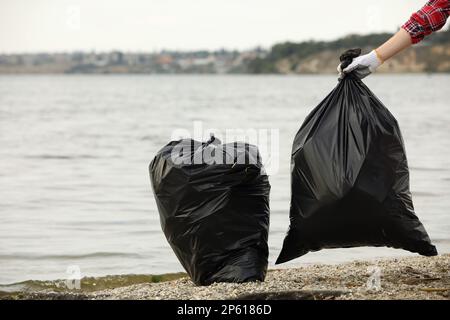 Frau mit Müllsäcken voll Müll am Strand, Schließung Stockfoto