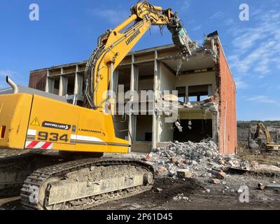 Hydraulikbagger mit Hydraulikhammer zum Abriss eines Industriegebäudes, einer Abbruchstelle. Stockfoto