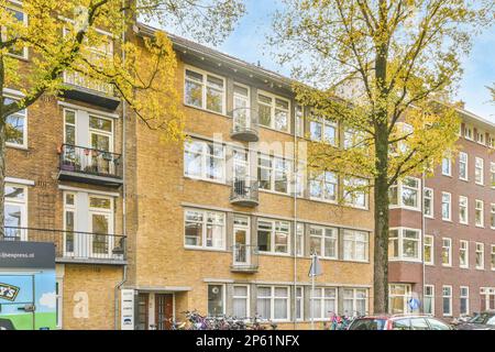 Amsterdam, Niederlande - 10. April 2021: Ein Wohnkomplex in den niederlanden mit Fahrrädern auf der Straße und Autos auf der Straße Stockfoto