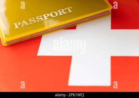 Schweizer Flagge mit Reisepass. Reisevisum und Staatsbürgerschaftskonzept. Aufenthaltstitel im Land. Ein gelbes Dokument mit der Aufschrift Passpo Stockfoto