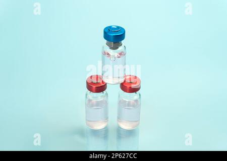 Medizinische Glasfläschchen für transparente Flüssigkeitsproben auf blauem Hintergrund. Medizin, Pharmakologie, Labor, Produktionsmakro Stockfoto