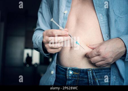 Die Hand des jungen Mannes mit der Insulinspritze in der Nahaufnahme. Insulininjektion zu Hause. Selbstmedikation Stockfoto