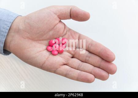 Rote Pillen in der Hand eines Mannes Nahaufnahme. Der Begriff der Behandlung. Antivirales Mittel. Draufsicht Stockfoto