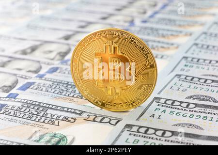 goldene Bitcoin-Münze auf US-Dollar. Konzept des elektronischen Geldwechsels. Stockfoto