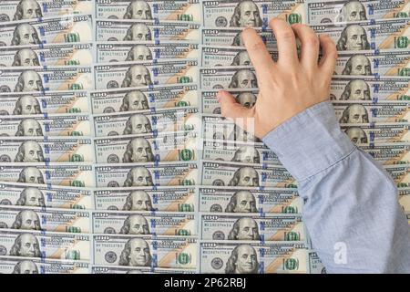 Hand mit US-Dollar-Scheinen auf grauem Hintergrund. Amerikanisches Geld. Reicher Mann Stockfoto