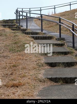 Treppen aus Stein und ein Handlauf aus Metall führen nach oben Stockfoto