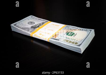 10.000 Dollar in einem Bündel auf schwarzem Hintergrund. Business Saving-Konzept. Viel Geld. Stockfoto