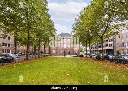 Amsterdam, Niederlande - 10. April 2021: Ein Apartmentkomplex mit Bäumen und Autos auf dem Rasen vor dem thematischen Gebäude in amsterdam Stockfoto
