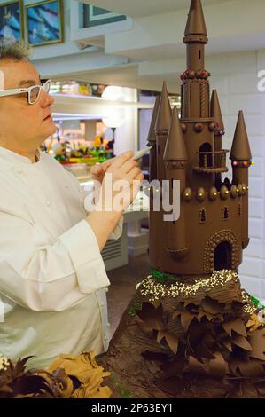 Christian Escriba und eine Assistentin, die einen 'MonaÂ', typischen Schokoladenkuchen von PascuaÂ montag, zubereitet, gibt der Patenonkel seinem Patensohn, der katalanischen Tradition, ESCR Stockfoto