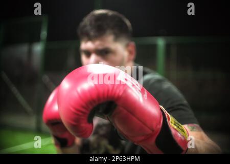 Boxer wirft Jabs und schlägt mit Boxhandschuhen in Zeitlupe mit geringer Schärfentiefe vor die Kamera. Stockfoto