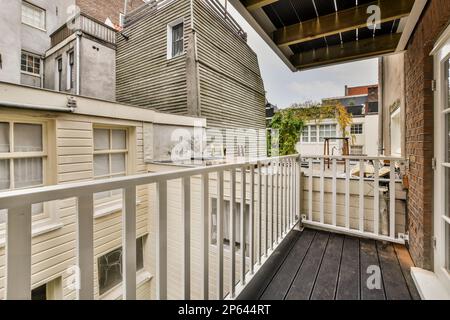 Amsterdam, Niederlande - 10. April 2021: Ein Balkon mit weißen Geländern und Holzfußboden auf der Außenseite einer Wohnung in london, england Stockfoto