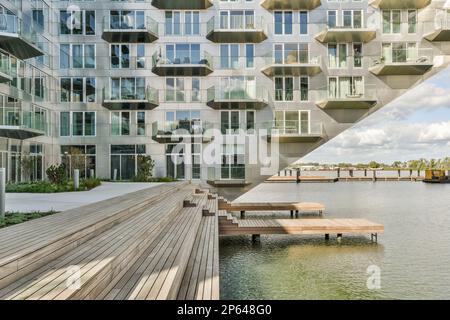 Ein Gebäude mit vielen Fenstern an der Seite und einem Dock im Vorderbereich – das Bild wird aus einem Winkel aufgenommen Stockfoto