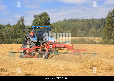 Landwirt, der auf dem Feld mit Traktor und Kverneland Taarup Zwillingsrechen arbeitet und an einem Tag im Spätsommer trockenes Stroh harkt. Salo, Finnland. 27. August 2022. Stockfoto