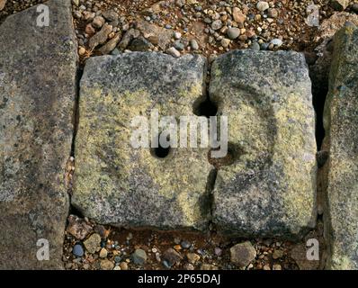 Defekte Steinabflussabdeckung am Rand der Stanegate Roman Road, Corbridge Roman Town, Northumberland, England, Großbritannien. Stockfoto