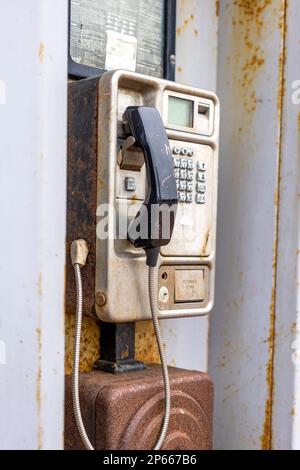 Dreckige, alte, münzbetriebene Telefonzelle, rostig und unbenutzt Stockfoto