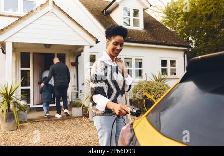 Frau, die ein Ladegerät in das Auto steckt Stockfoto