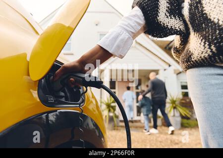 Frau, die ein Ladegerät in das Auto steckt Stockfoto