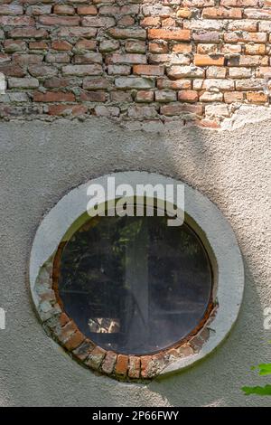 Ein rundes Fenster in einem alten, zerstörten Gebäude. Stockfoto