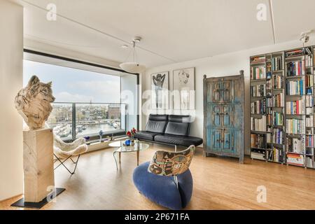 Ein Wohnzimmer mit Büchern auf den Regalen und eine Katzenstatue in der Ecke neben den Bücherregalen Stockfoto