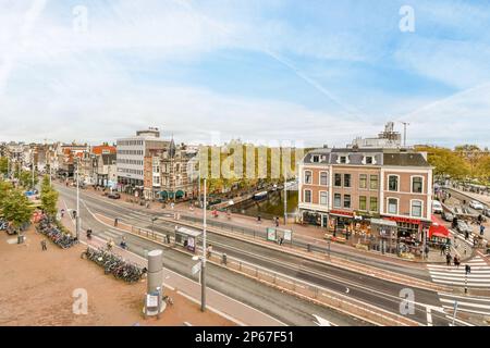 Eine Stadt mit Gebäuden und Menschen, die auf den Gehwegen vor Geschäften, Cafés, Restaurants und Geschäften spazieren Stockfoto