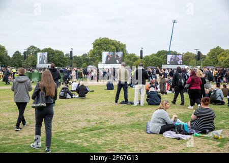 Im Hyde Park, London, treffen sich Menschen, wo die Fernsehübertragung des Todestages der verstorbenen Königin Elizabeth II. Auf großen Bildschirmen gezeigt wird. Stockfoto