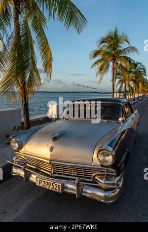 Klassisches silbernes Ford Auto parkt auf einsamer Küstenstraße, Raffinerie im Hintergrund, Cienfuegos, Kuba, West Indies, Karibik, Mittelamerika Stockfoto