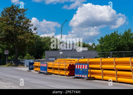 Ein Stapel oranggelber PVC-Leerrohre entlang der Straße. Baustelle in der Stadt. Stockfoto