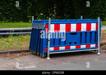 Auf dem Bürgersteig befinden sich bewegliche Absperrungen aus Kunststoff für Zäune in blau-rot-weiß. Schließen. Stockfoto