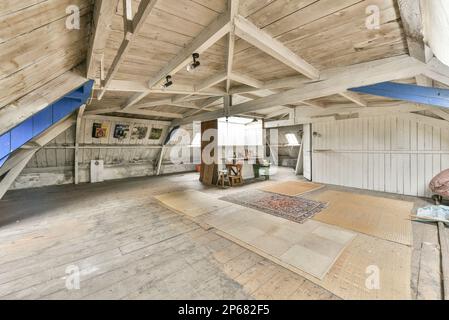 Ein unvollendeter Raum mit Holzfußboden und Wänden an der Decke, die in Blau, Weiß und Grau gestrichen sind, ist sichtbar Stockfoto