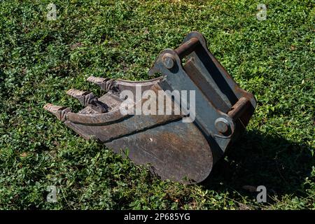 Baggerlöffel liegt auf grünem Gras. Schließen. Stockfoto