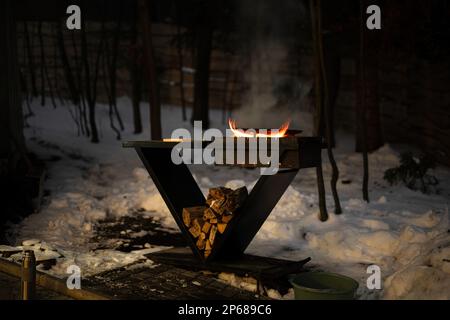 Holzfeuer-Barbecue mit brutzelnder Flamme am Abend. Stockfoto