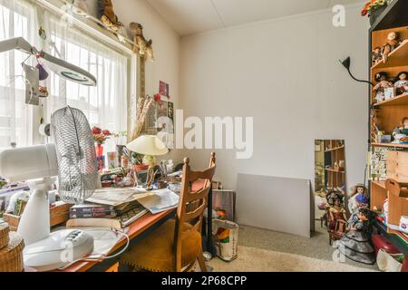 Ein chaotisches Heimbüro mit vielen Klamotten auf dem Schreibtisch und Regalen vor dem Computerbildschirm Stockfoto