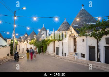 Weiße Trulli-Häuser entlang der Via Monte San Michele in der Altstadt, beleuchtet in der Abenddämmerung, Alberobello, UNESCO-Weltkulturerbe, Apulien, Italien Stockfoto