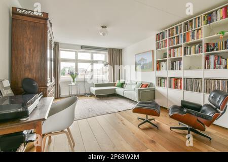 Ein Wohnzimmer mit einigen Büchern auf den Regalen und ein Bürostuhl im Zimmer ist voller Holzfußboden Stockfoto