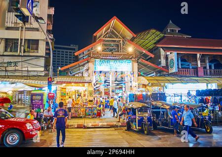 CHIANG MAI, THAILAND - 3. MAI 2019: Beleuchteter Pavillon des Nachtmarkts Kalare mit kleinen Verkaufsständen und geparkten Tuk-Tuk-Taxis im Vordergrund, o Stockfoto