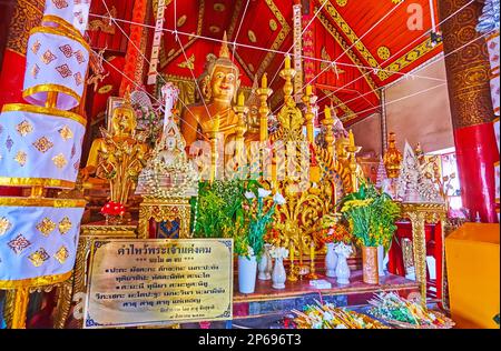 CHIANG MAI, THAILAND - 3. MAI 2019: Der Altar in Viharn von Wat Si Koet mit goldenen Buddha-Bildern, Kerzen und Blumenopfern, Chiang Mai Stockfoto