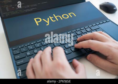 Ein Programmierer schreibt ein Programm in Python. Männliche Hände auf einer schwarzen Tastatur Stockfoto
