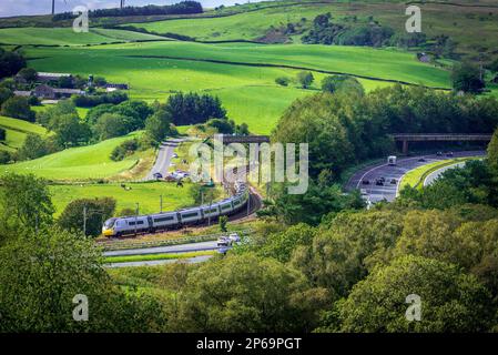 Ein Avantini Pendolino Kippzug auf den Kurven auf der West Coast Hauptlinie bei Beck Foot bei Tebay gesehen, mit der M6 läuft neben. Stockfoto