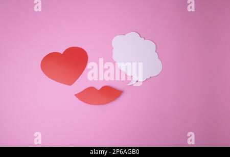 Auf einem rosa Hintergrund Papier rote Lippen und ein Herz und eine weiße Wolke für Worte. Stockfoto