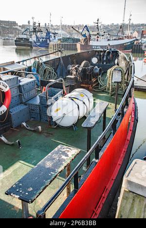 Sehen Sie sich den Hafen von Whitby an, wo Fischereifahrzeuge aneinander hängen und verschiedene dazugehörige Gegenstände auf dem Kai sind. Whitby, Yorkshire Moors National Park. Stockfoto