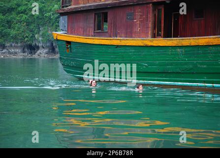 Touristen schwimmen in der spektakulären Halong-Bucht, die zum Weltkulturerbe in Vietnam gehört Stockfoto