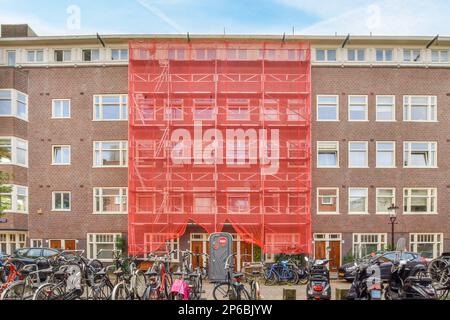 Einige Fahrräder parkten vor einem großen roten Backsteingebäude mit vielen Fenstern und Buden an der Seite Stockfoto