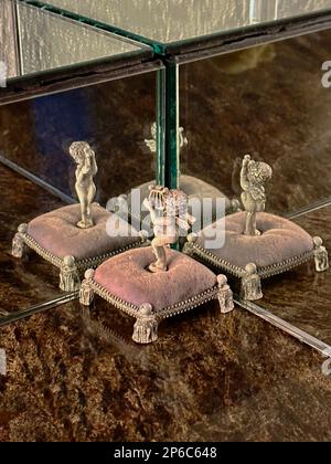 Die Harfen spielenden Cherubs auf Sockeln oder Kissen zeigen eine dreifache Spiegelreflexion mit Marmorsockel. Die Figuren sind Engelsfiguren mit weichen pinkfarbenen Sockelfüßen. Stockfoto