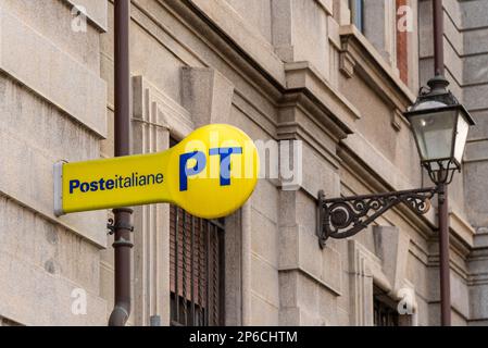 Cuneo, Italien - 11. April 2022: PT Poste Italiane, Italien das Logo auf dem gelben Schild neben dem alten Laternenpfahl vor dem italienischen Postamt anbringen. Posteit Stockfoto