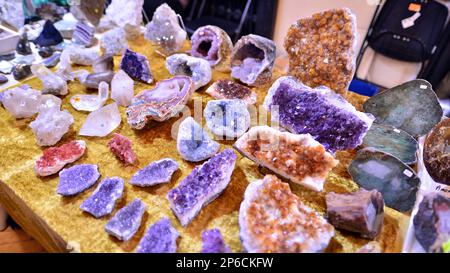 Warschau, Polen. 5. März 2023 Warschauer Mineralausstellung 2023. Farbige Steine unterschiedlicher Größe liegen auf einem Regal. Ausstellung von Halbedelsteinen. Stockfoto
