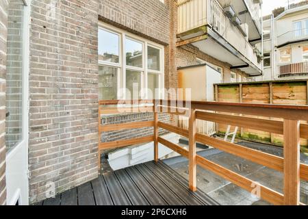 Amsterdam, Niederlande - 10. April 2021: Das Äußere eines Hauses mit Holzgeländern und Treppen, die zu einem Balkon auf der oberen Ebene führen, der aus Ziegeln besteht Stockfoto