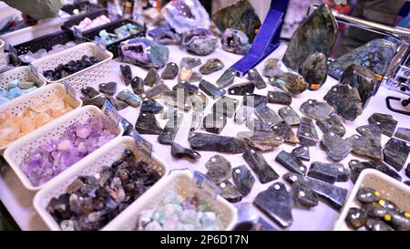 Warschau, Polen. 5. März 2023 Warschauer Mineralausstellung 2023. Farbige Steine unterschiedlicher Größe liegen auf einem Regal. Ausstellung von Halbedelsteinen. Stockfoto