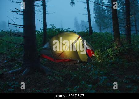 Grünes, leichtes, freistehendes, dreijähriges Zelt für 2 Personen auf dem Wald am Morgen nach Regen in den Beskid Mountains Stockfoto